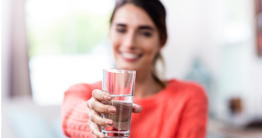 Jovem mulher mostrando copo com água para a câmera