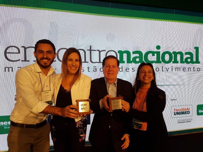Colaboradores da Unimed Fortaleza ao lado do Diretor Comercial, Dr. João Borges, segurando os prêmios recebidos pela Unimed Brasil.