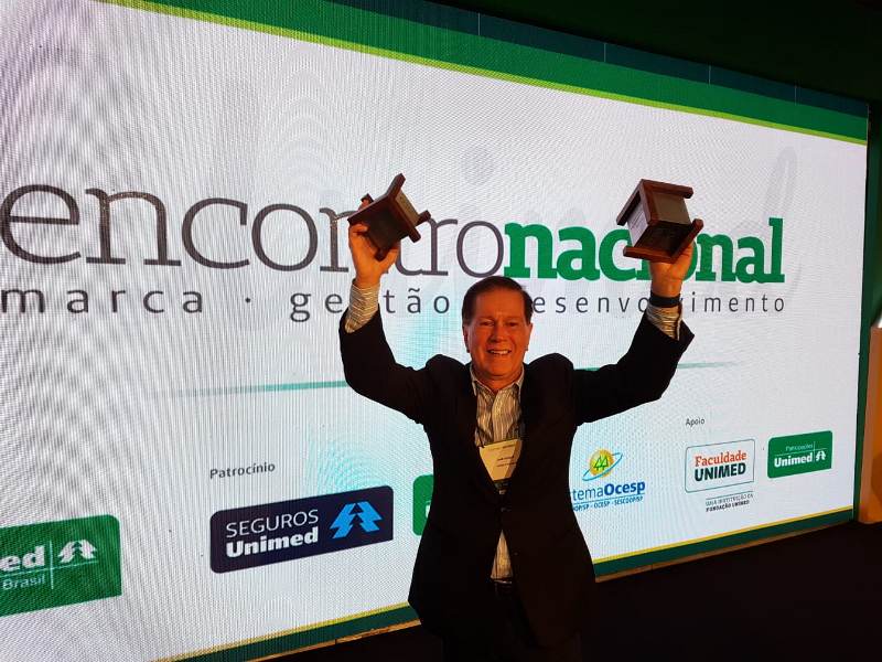 Diretor comercial, Dr. João Borges, segurando os dois prêmios recebidos pela Unimed Brasil.