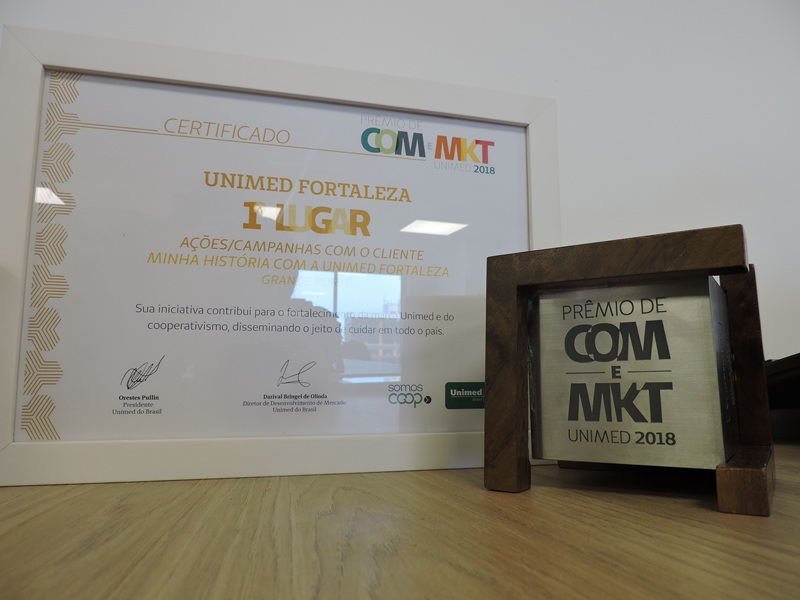 Certificado de homenagem ao lado do prêmio de 1º lugar na categoria Ações/Campanhas com o cliente
