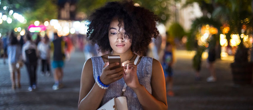 Mulher mexendo em celular na rua