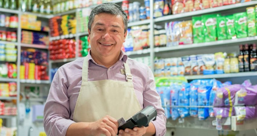 Proprietrio em seu mercadinho sorrindo para a cmera