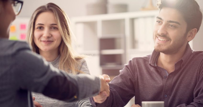 Funcionrio sorridente cumprimenta sua gestora com um aperto de mo e celebra o novo plano de cargos e salrios da empresa