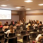 Participantes assistindo palestra no evento especial do Dia da Mulher