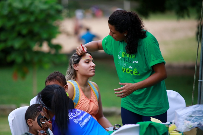 Mulheres pintando o rosto de crianas e adultos durante o evento