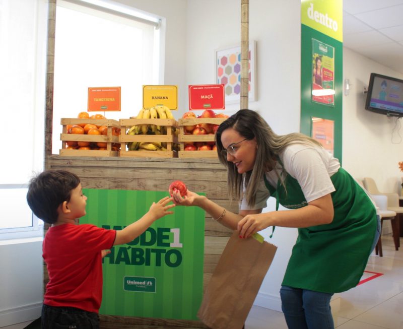 Criana recebendo fruta de uma mulher