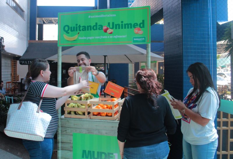 Pessoas em volta da Quitanda Unimed com frutas