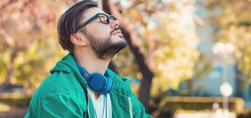 Homem de olhos fechados respirando ao ar livre sem sintomas de rinite