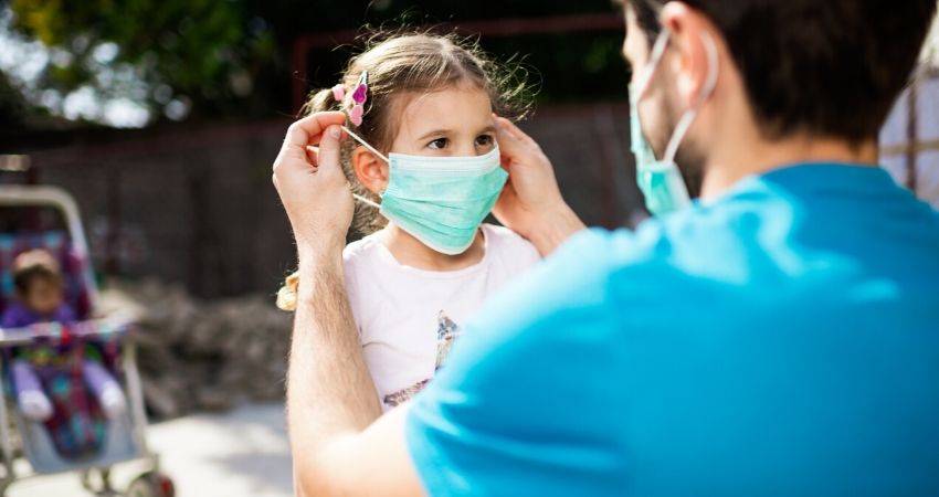 Pai colocando mscara de proteo na filha para evitar a contaminao pelo coronavrus