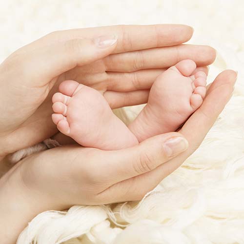 Mãos segurando os pés do bebê