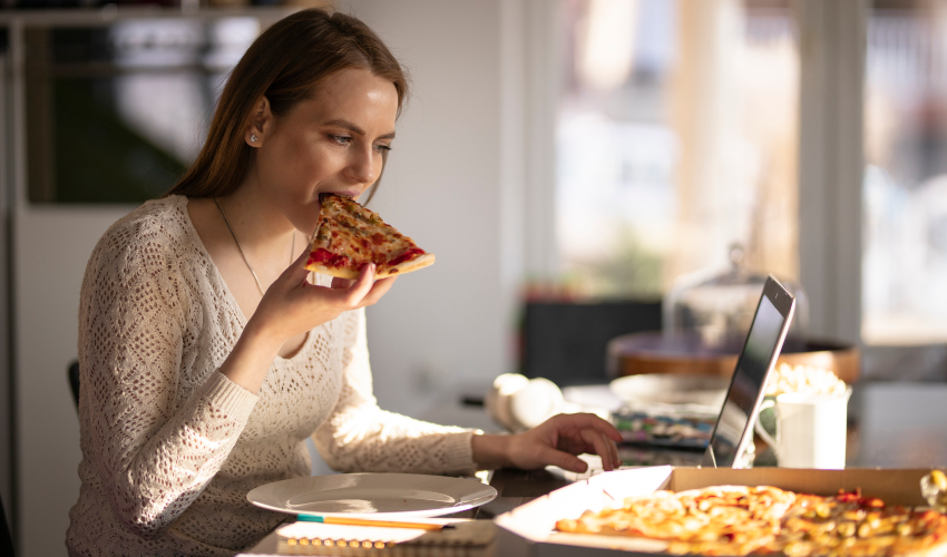 mulher comendo pizza motivada pela fome emocional