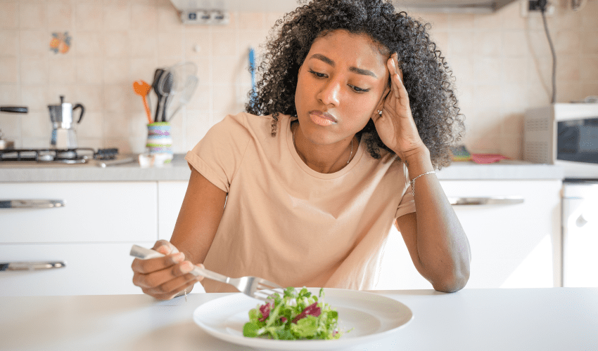 Mulher com falta de apetite olhando para prato com comida